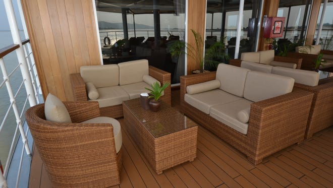 Rattan furniture is arranged in seating areas on the open-air deck.