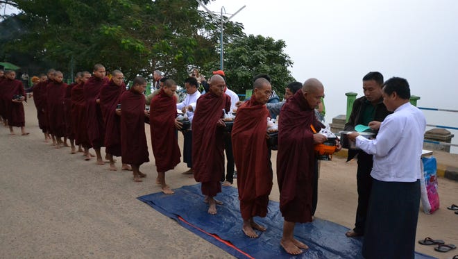 Avalon Myanmar crew members give alms to Buddist monks during a stop at the Irrawaddy River town of Katha.