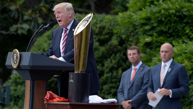 President Donald Trump speaks next to Clemson's national championship trophy during a ceremony on the South Lawn of the White House celebrating the school's title.
