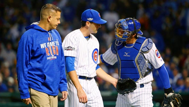 Game 2 at Chicago: Cubs starting pitcher Kyle Hendricks walks off the field with athletic trainer P.J. Mainville after being hit with a ball during the fourth inning.
