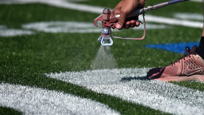 A worker touches up the logo at center field for the football game between Tennessee and Virginia Tech at Bristol Motor Speedway.