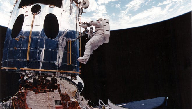 Astronaut F. Story Musgrave, is reflected in the shiny surface of the Hubble Space Telescope as he works with a portable foot restraint on Dec. 7, 1993.