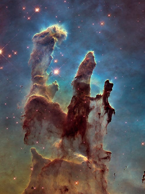 This Hubble Space Telescope shows one of its most iconic and popular images: the Eagle Nebulas Pillars of Creation. This image shows the pillars as seen in visible light, capturing the multi-colored glow of gas clouds, wispy tendrils of dark cosmic dust, and the rust-coloured elephants trunks of the nebulas famous pillars.