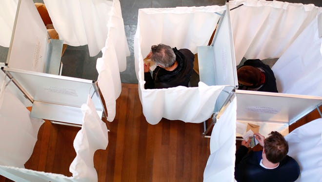 Voters pick their candidates inside voting booths at a polling station in Paris on April 23, 2017 during the first round of the French presidential election.