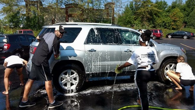Franklin High School cheerleaders hose down a car at the car wash fundraiser Aug. 19. The FHS cheer team, football team, and others all volunteered Aug. 19 to help support the Noyes family.