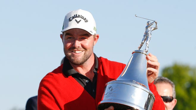 Marc Leishman holds the champions trophy and wears the red memorial sweater after winning the Arnold Palmer Invitational golf tournament at Bay Hill Club & Lodge .