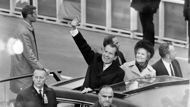 President Richard Nixon waves as he and first lady Pat Nixon stand in the limousine carrying them from the inauguration at the Capitol to the White House on Jan. 20, 1969.