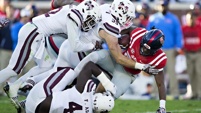 Mississippi State’s Richie Brown and company tackle Ole Miss running back Eugene Brazley during Saturday’s Egg Bowl, won by the Bulldogs 55-20 at Vaught-Hemingway Stadium in Oxford.