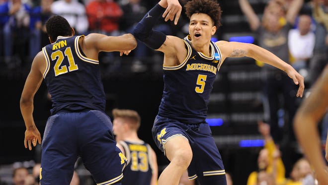 Michigan's D.J. Wilson celebrates with teammate Zak Irvin after the Wolverines beat Louisville in their second-round NCAA tournament game.