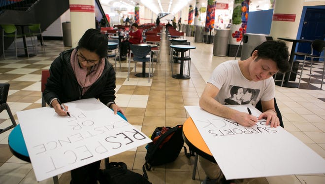 Anjali Fernandes, left, and Ian Maynor, of Boston, make protest signs inside the cafeteria at Union Station in Washington, ahead of the 2017 Presidential Inauguration.