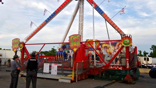 Authorities stand near the Fire Ball amusement ride after the ride malfunctioned injuring several at the Ohio State Fair, Wednesday, July 26, 2017, in Columbus, Ohio. Some of the victims were thrown from the ride when it malfunctioned Wednesday night, said Columbus Battalion Chief Steve Martin.