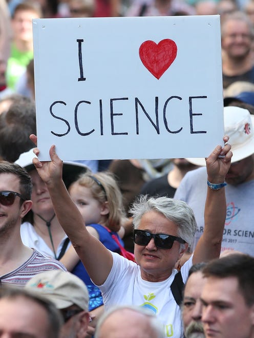 People stand together holding placards during the March for Science day at Martin Place in Sydney, Australia.
