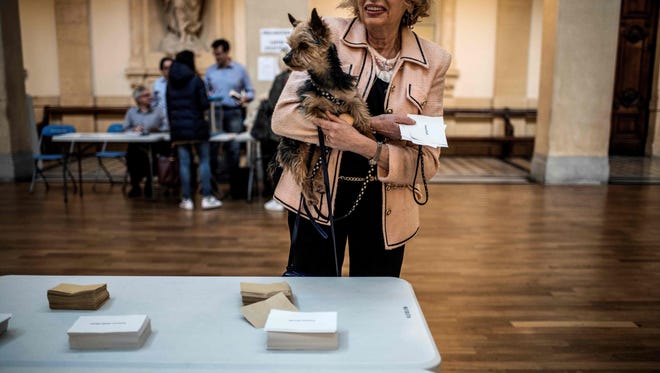 A woman carries her dog as she casts her ballot at a polling station in Lyon, on April 23, 2017, during the first round of the presidential elections.