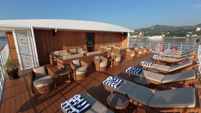 The top deck of the Avalon Myanmar features a sun deck with cushioned lounge chairs.