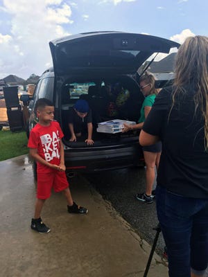 Carson Boutte, 9, of Youngsville, La., who is getting out of his parents' SUV, helped deliver 363 pizzas to flood victims Aug. 20, 2016. Others in the community also bought food in his name.