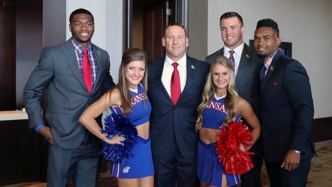 Kansas Jayhawks head coach David Beaty (middle) poses for a photo with cheerleaders and quarterback Montell Cozart (left) and linebacker Joe Dineen Jr. (second to right) and defensive back Fish Smithson (right) during the Big 12 Media Days at Omni Dallas Hotel.
