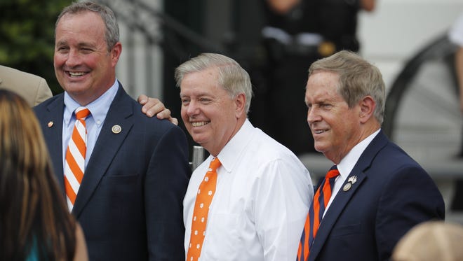 Sen. Lindsey Graham, R-S.C., center, flanked by Rep. Jeff Duncan, R-S.C., left, and Rep. Joe Wilson, R-S.C., stands on the South Lawn of the White House during a celebration for Clemson's football national championship.