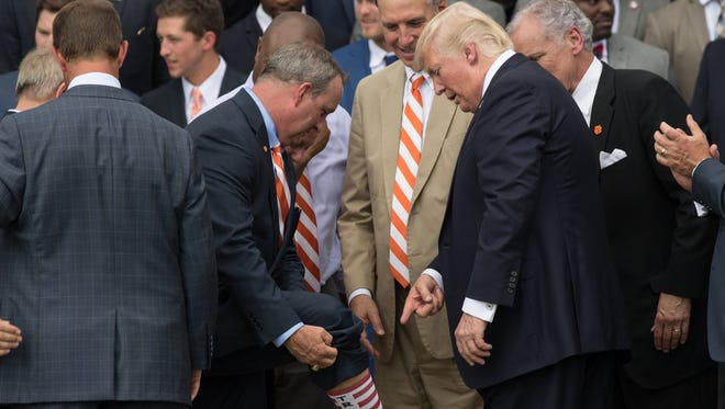 Jeff Duncan shows President Donald Trump his Trump socks during a ceremony on the South Lawn of the White House celebrating Clemson's football national championship.