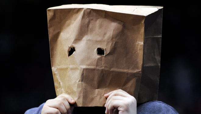 A fan with a paper bag over his head watches a game between the Nets and the Heat.