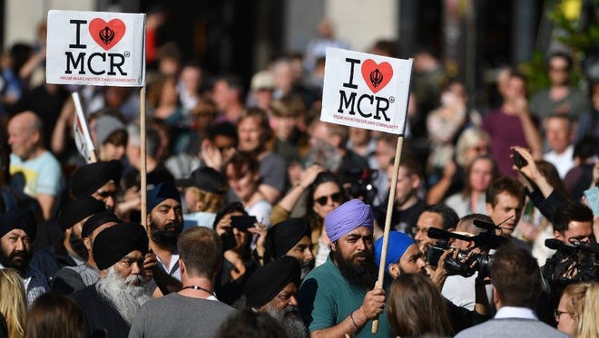 People from the Manchester Sikh community carry "I love MCR" banners as they arrive to attend a vigil in Albert Square in Manchester, on May 23.