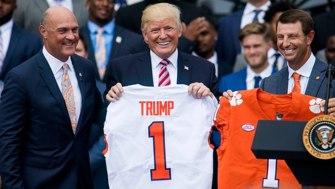 President Trump and Clemson football coach Dabo Swinney holds up a jerseys during a ceremony on the South Lawn of the White House celebrating Clemson's football national championship.