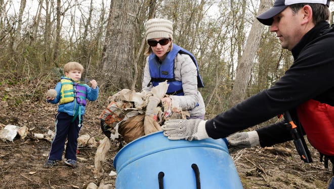 Rhyan Shea Wheeler loads trash into a barrel with Jason El Koubi and his son, Marc, along the banks of the Vermilion during a clean-up project held by Bayou Vermilion District and No Waste Louisiana Saturday, Feb. 4, 2017.