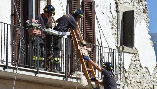 Firefighters help people to recover their personal belongings from damaged houses in the village of Rio, Italy, on August 28, 2016.