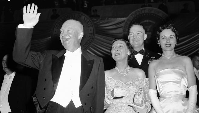 Eisenhower waves as he arrives at the National Guard Armory with wife Mamie and his son and daughter-in-law, Maj. John Eisenhower and Barbara Eisenhower, to attend an inaugural ball on Jan. 21, 1957.