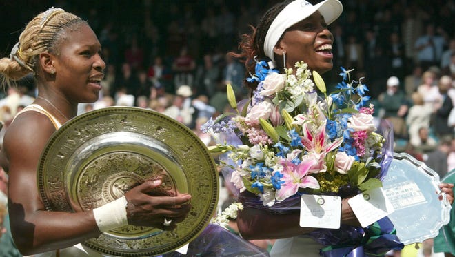 Serena Williams, left, holds her trophy after defeating her sister Venus, to win the Wimbledon women's singles final.