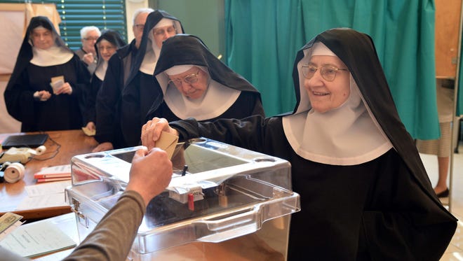 A Benedictine sister of the Sainte-Cecile Abbey casts her ballot at a polling station in Solesmes, France, during the first round of the French presidential election.