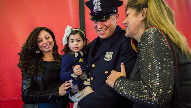 Matias Ferreira, center, celebrates with his 2-year-old daughter, his wife, left, and his mother during his graduation from the Suffolk County Police Department Academy at the Health, Sports and Education Center in Suffolk, Long Island, New York, on Friday.
