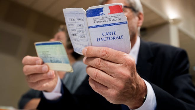 An assessor verifies the identity of a voter in the first round of the French presidential elections in Tulle, France, on April 23, 2017. France will hold the second round of the presidential elections May 7, 2017.