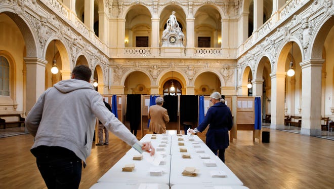People pick up ballots before voting for the first round of the presidential election in Tulle, France.