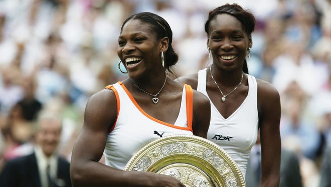 Serena Williams (left) holds the 2003 Wimbledon trophy after beating her sister Venus in the women's singles final.