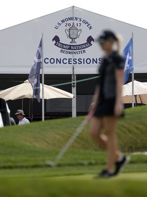 A golfer walks past a tent bearing the logo of Trump National Golf Club during a practice round at the U.S. Women's Open Golf Championship on Wednesday.