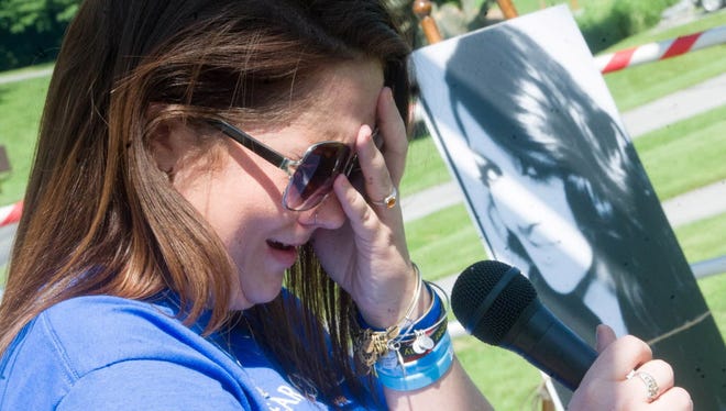 Alyssa Fiorentino breaks down in tears as she attempts to read a poem about her sister, Brooke, seen in a photograph in the background, during a heroin awareness vigil at Kain Park in July 2015.