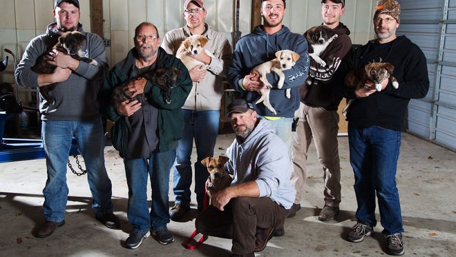 In this Wednesday, Oct. 26, 2016 photo, from left, Jake Rowe holding Knox, Joe Gruber holding Bear, Alex Manchester holding Rosie, Doug Craddock with Annie, Mitchel Craddock holding Brimmie, Brent Witters holding Finn and Dexter Jennings holding Gunner pose for a photo in Vicksburg, Mich. It all started the morning of Mitchel Craddock's 5-day bachelor getaway, a four-wheeling trip to Tennessee arranged by the Best Man in Craddock's Oct. 8 wedding. Friends of Mitchel Craddock, the bridegroom-to-be, each came home from his bash with a puppy. (Bryan Bennett/Kalamazoo Gazette-MLive Media Group via AP)