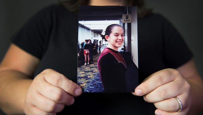 Kelly Cutright, who was abused by her gymnastics coach as a young teen and asked to be identified with her maiden name, holds a photo of herself as a gymnast when she was 15.