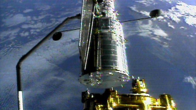 The Hubble space telescope is held by space shuttle Discovery's robot arm on Dec. 25, 1999 in preparation for its release from the shuttle. Discovery's seven person international crew redeployed the telescope after three days of repairs on this mission.