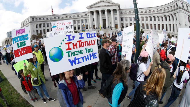 People carry signs and posters during a March for Science rally in Denver.