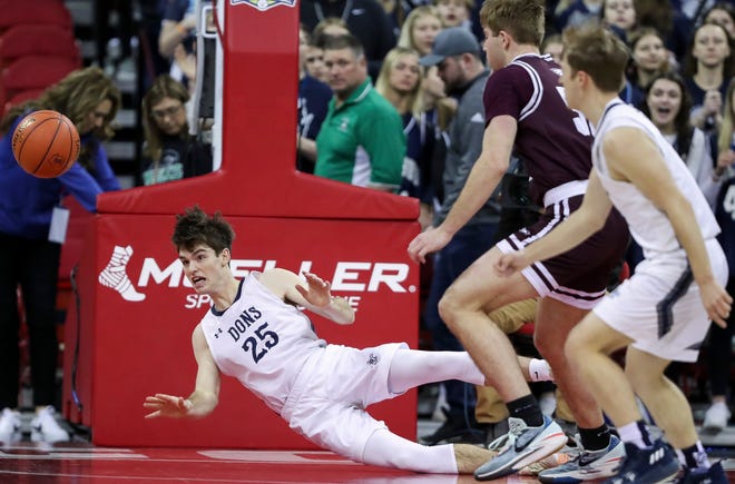 Columbus Catholic High School's Cy Becker (25) falls to the floor as he passes the ball against Solon Springs High School in a Division 5 semifinal game during the WIAA state boys basketball tournament on Friday, March 15, 2024 at the Kohl Center in Madison, Wis. Columbus Catholic won the game, 78-65.