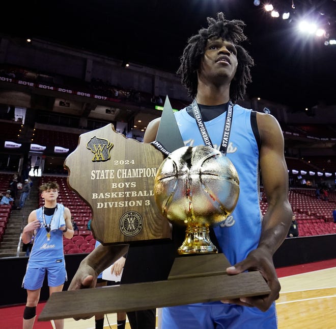 St. Thomas More's Amari McCottry (4) holds the WIAA Division 3 boys basketball state championship trophy after their victory over Lakeside Lutheran game on Saturday March 16, 2024 at the Kohl Center in Madison, Wis.
