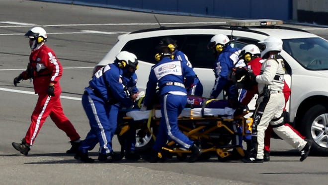 Safety workers attend to Denny Hamlin after his last-lap crash at the Auto Club 400 at Fontana, Calif., on March 24, 2013. Hamlin fractured a vertebrae in his back in the crash.