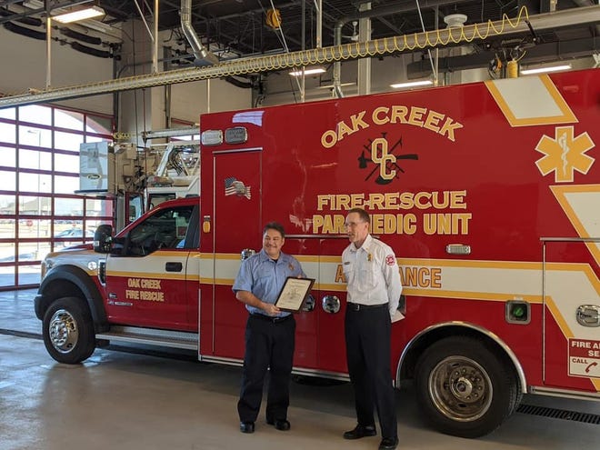 Michael Wargolet (left), a firefighter with the Oak Creek Fire Department, was recognized Feb. 28 by Chief Mike Kressuk (right) for his off-duty actions in saving an infant in Illinois Feb. 17.